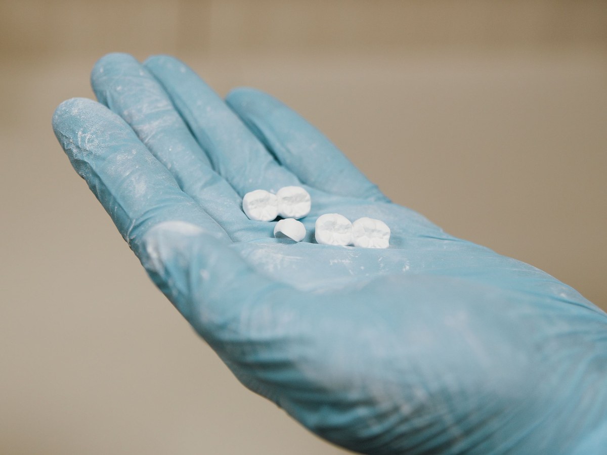 Gloved hand holding several small artificial teeth