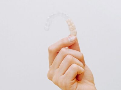 Hand holding a clear aligner against a white background