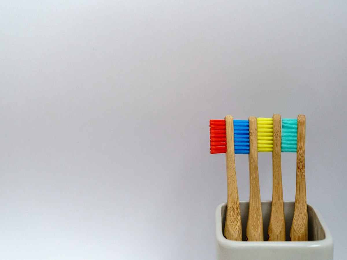 Four bamboo toothbrushes standing in a ceramic holder