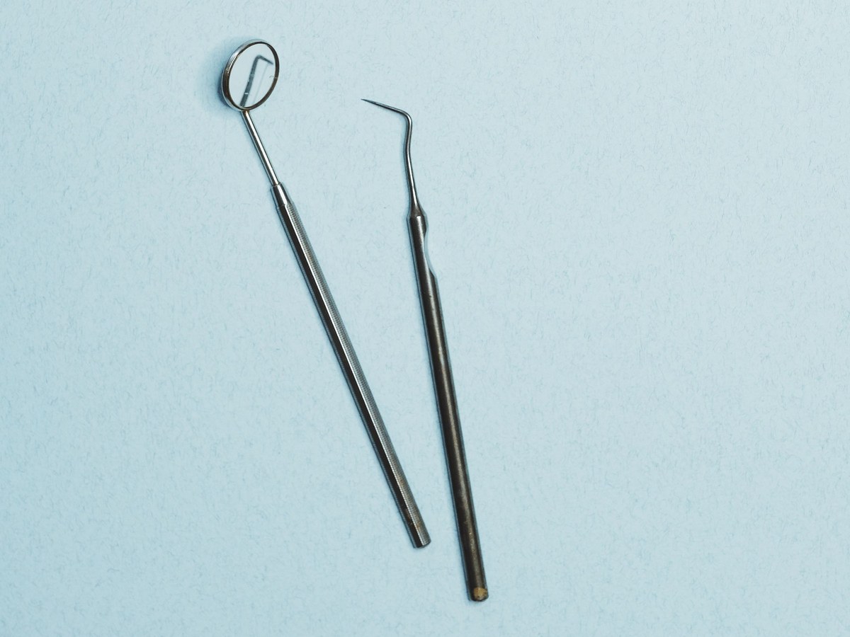 Dental mirror and explorer on a light blue surface