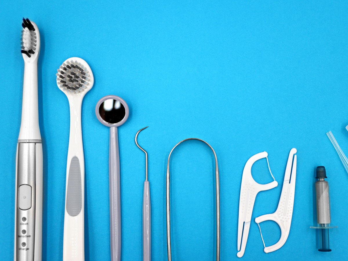 Toothbrushes, floss picks and a dental mirror on a blue surface