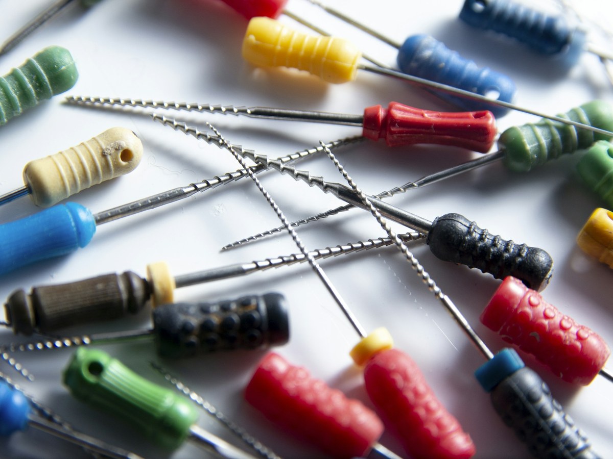 Root canal files with colored handles on a white surface
