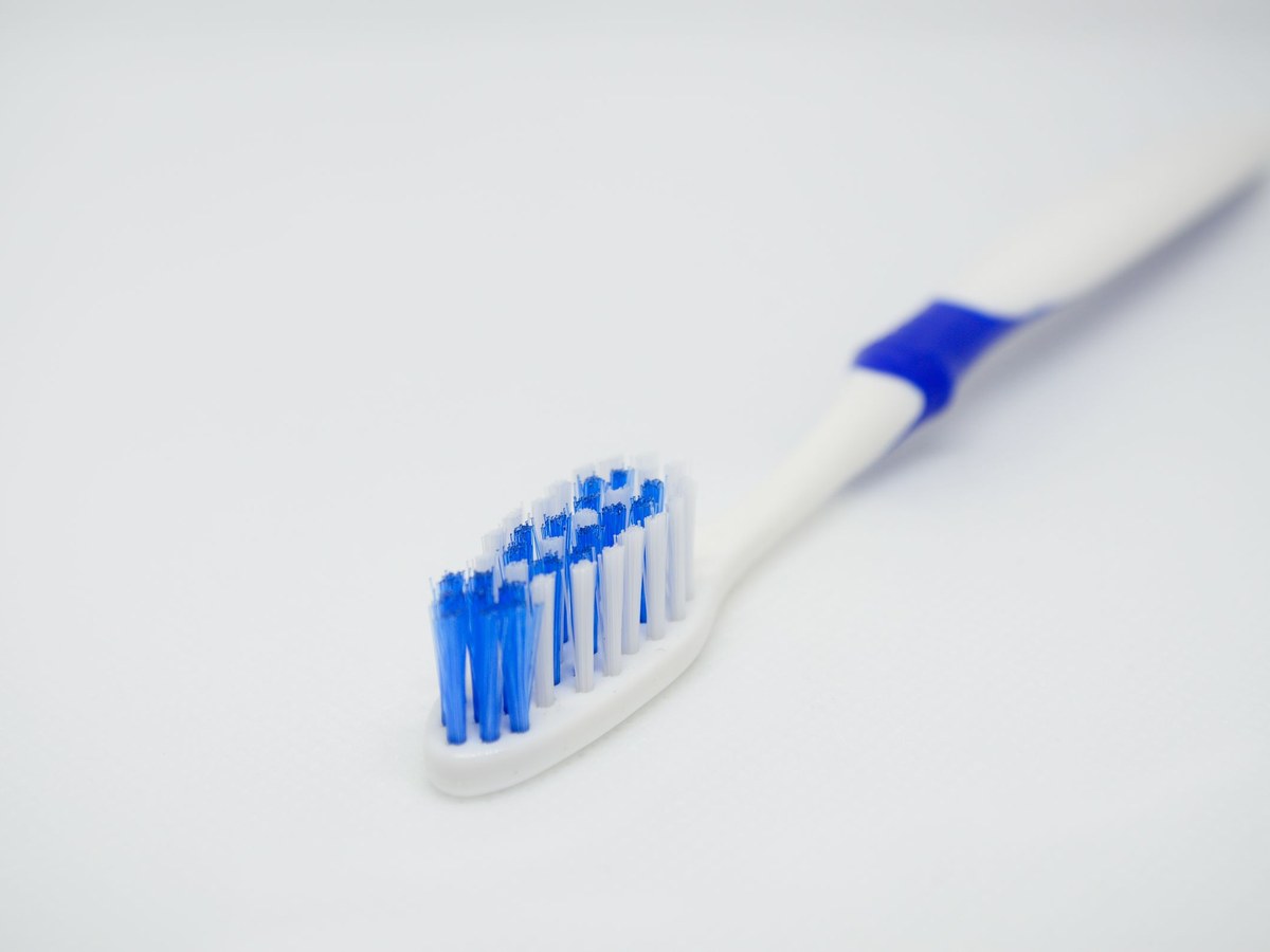 Blue and white toothbrush lying on a white surface