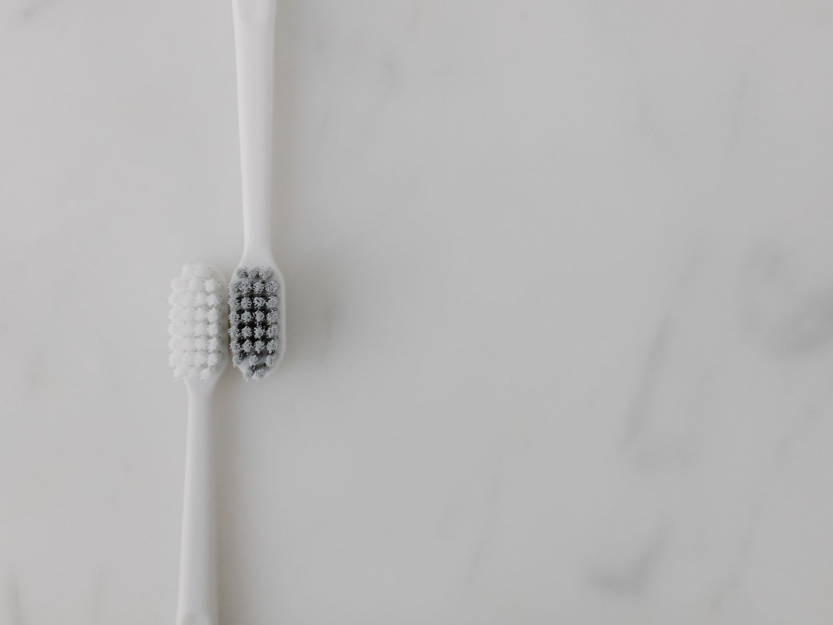 Two toothbrushes lying head to head on a marble surface